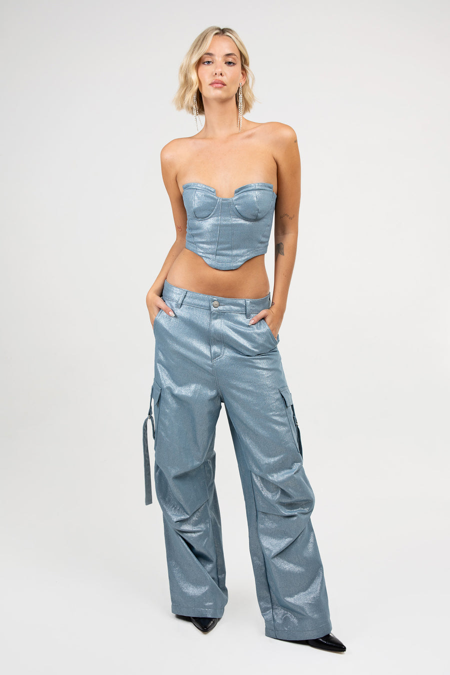 Modelo posando con Corset Blade de denim brillante con devoré, recortes y cierre en la espalda, en conjunto con Pantalón Blade.