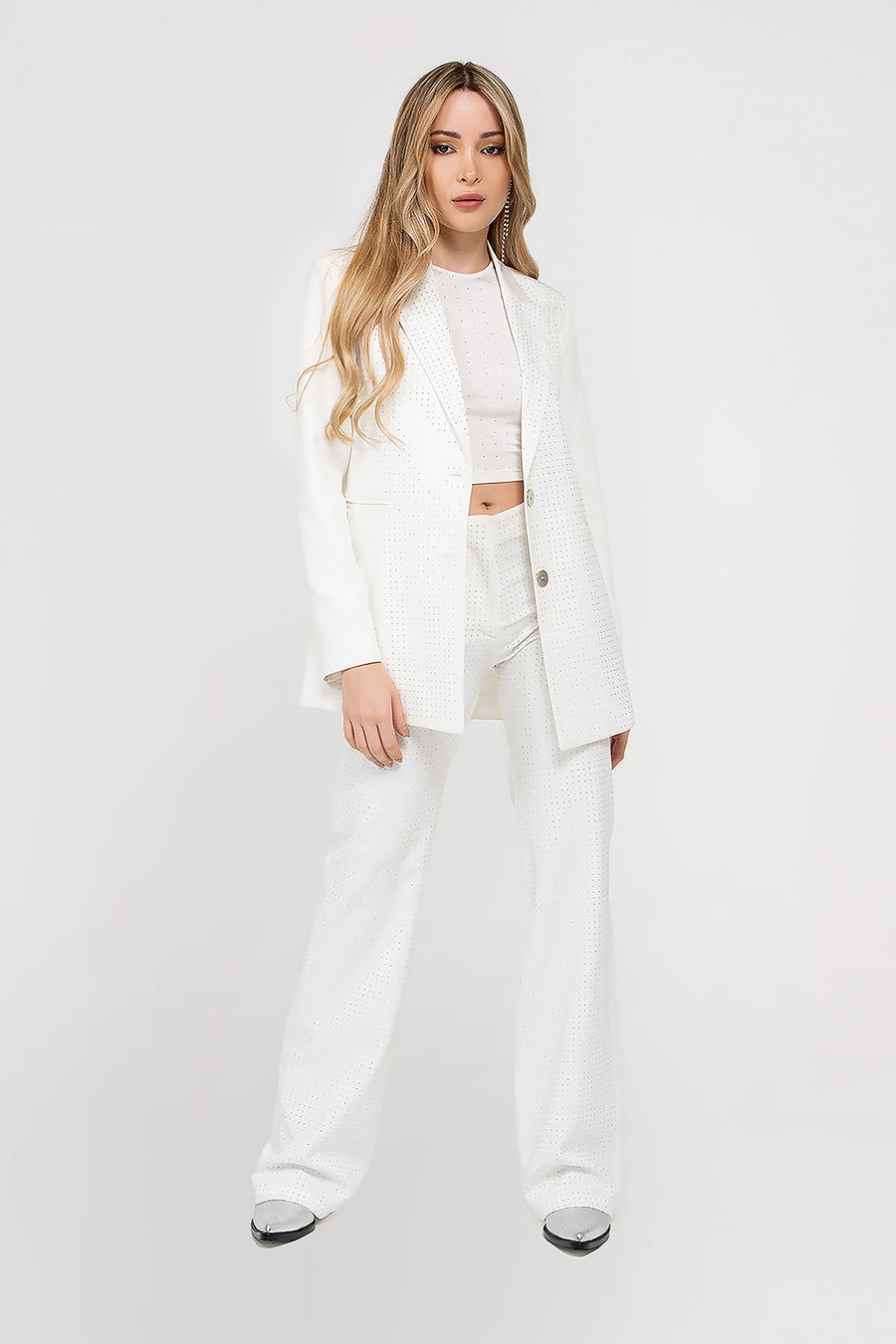 Modelo posando con Blazer Aurora sastrero de silueta regular con hotfix en toda la prenda, color Blanco. Total look con pantalón Aurora.