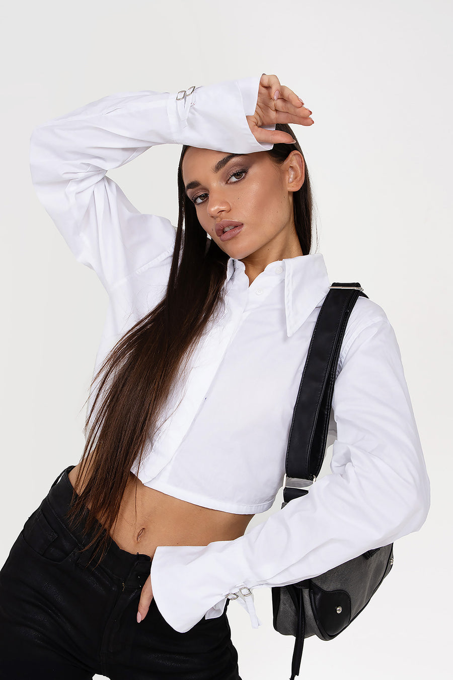 Modelo posando con Camisa Adrienne crop manga larga con puños Oxford y cuello en punto, espalda descubierta con pasadores para tiras ajustables.