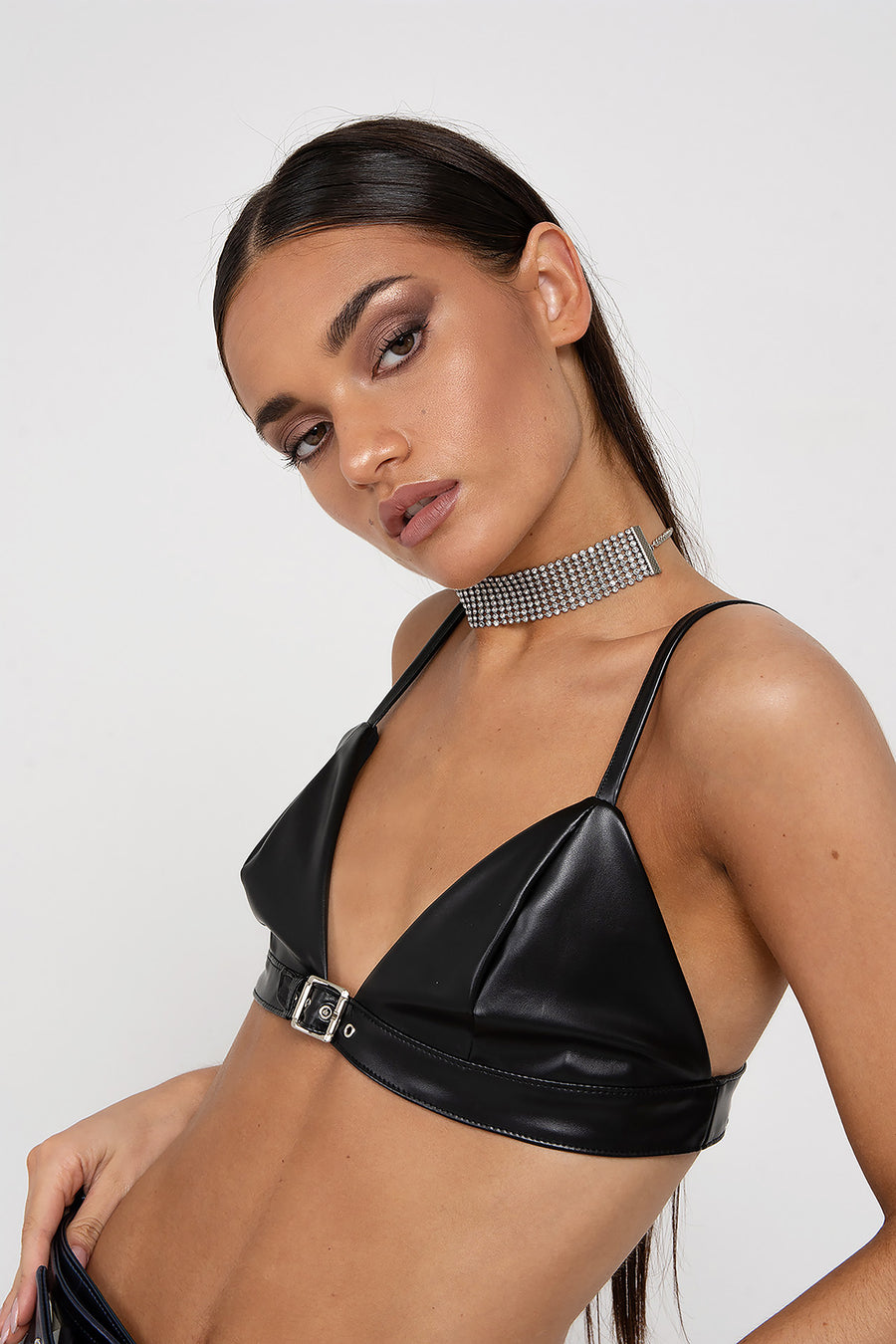 Modelo posando con Corpiño Harriet color negro de PU con un cautivador detalle de hebilla en la parte delantera.
