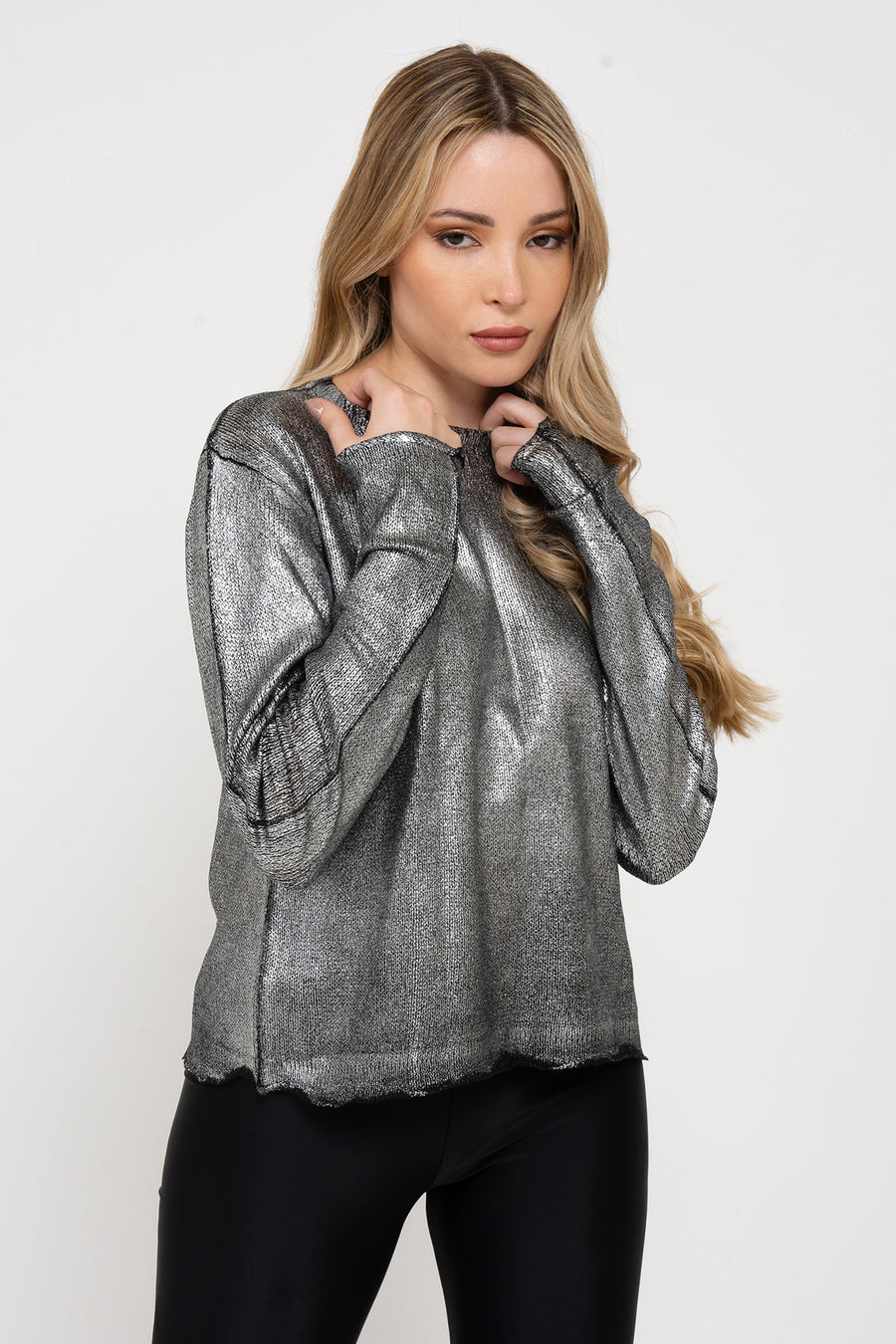 Modelo posando con Sweater Glam fino de foil plata con cuello redondo. Silueta regular y largo modular hasta la segunda cadera.