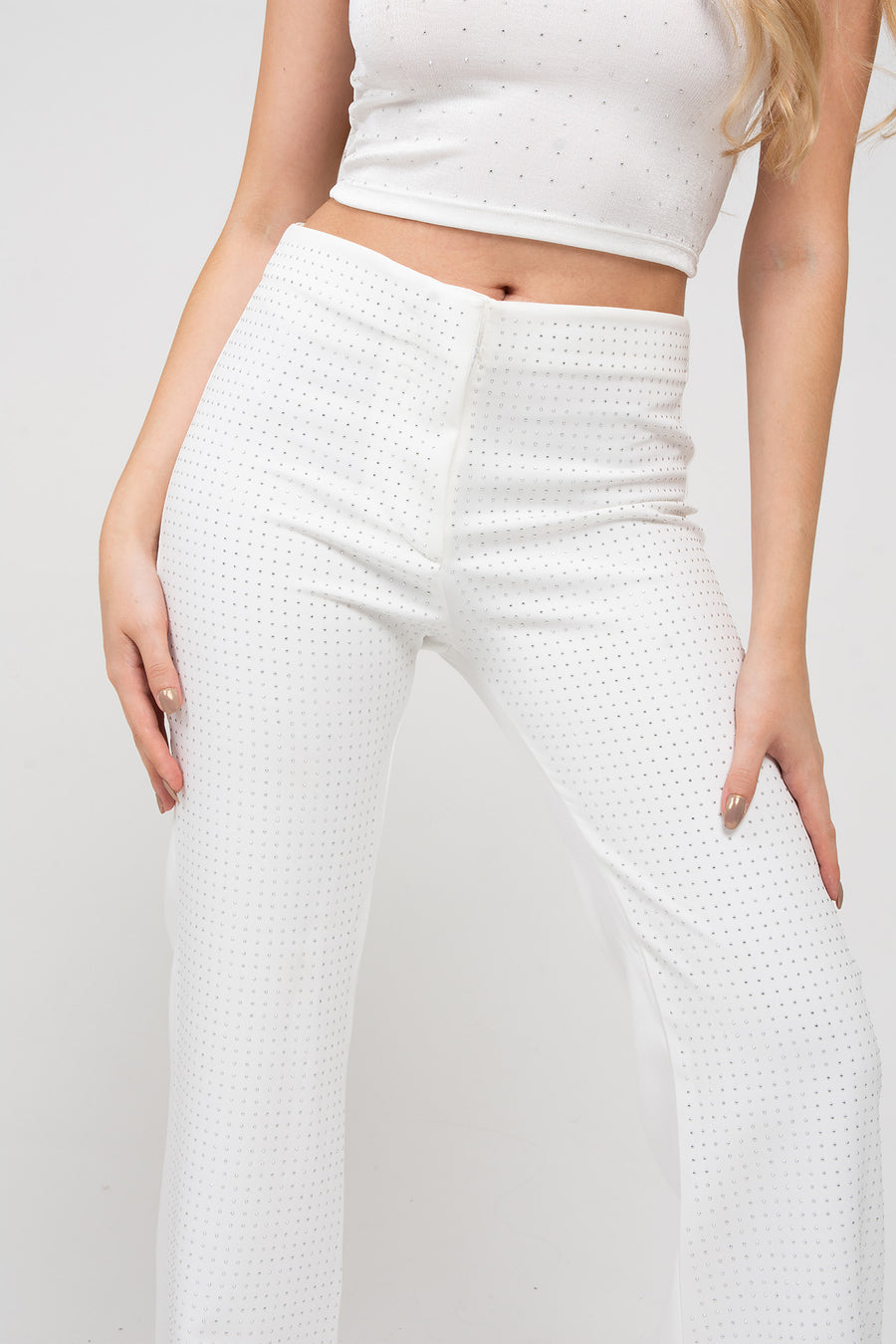 Foto detalle de modelo posando con Pantalón Aurora color blanco, sastrero recto y tiro medio, cuenta con full hotfix en delantero. 