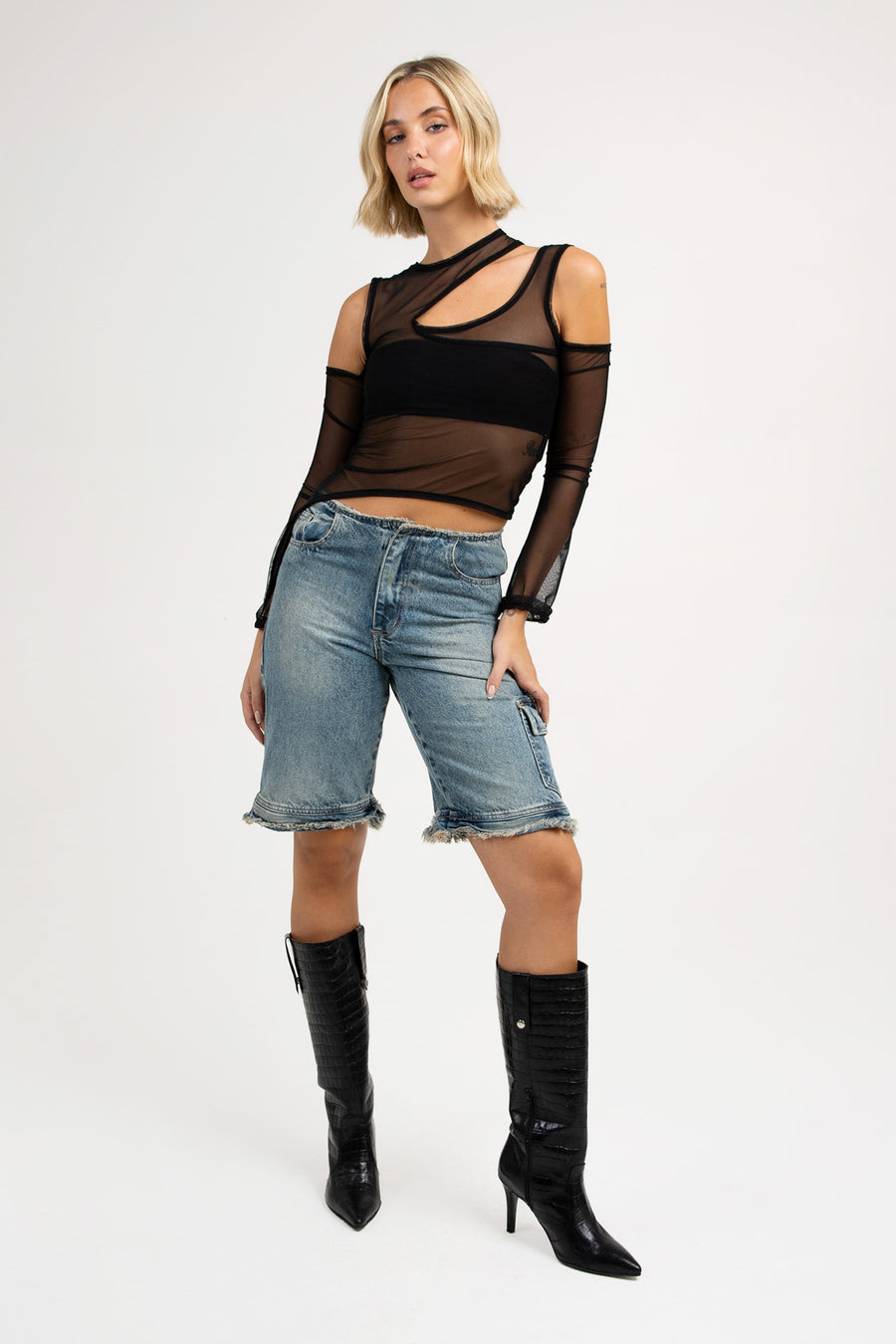 Modelo posando con Top Nesta asimétrico manga larga con recortes, color negro. 